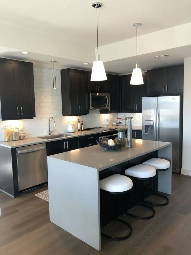 Modern kitchen with dark cabinets, stainless steel appliances, and a center island with bar stools.